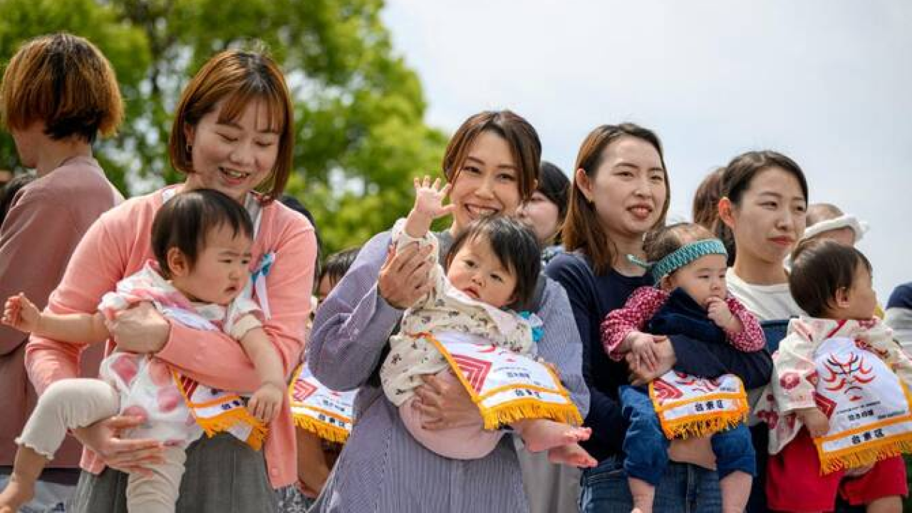 A Japanese family walking in a city park, symbolizing the nation’s declining birthrate and aging population.