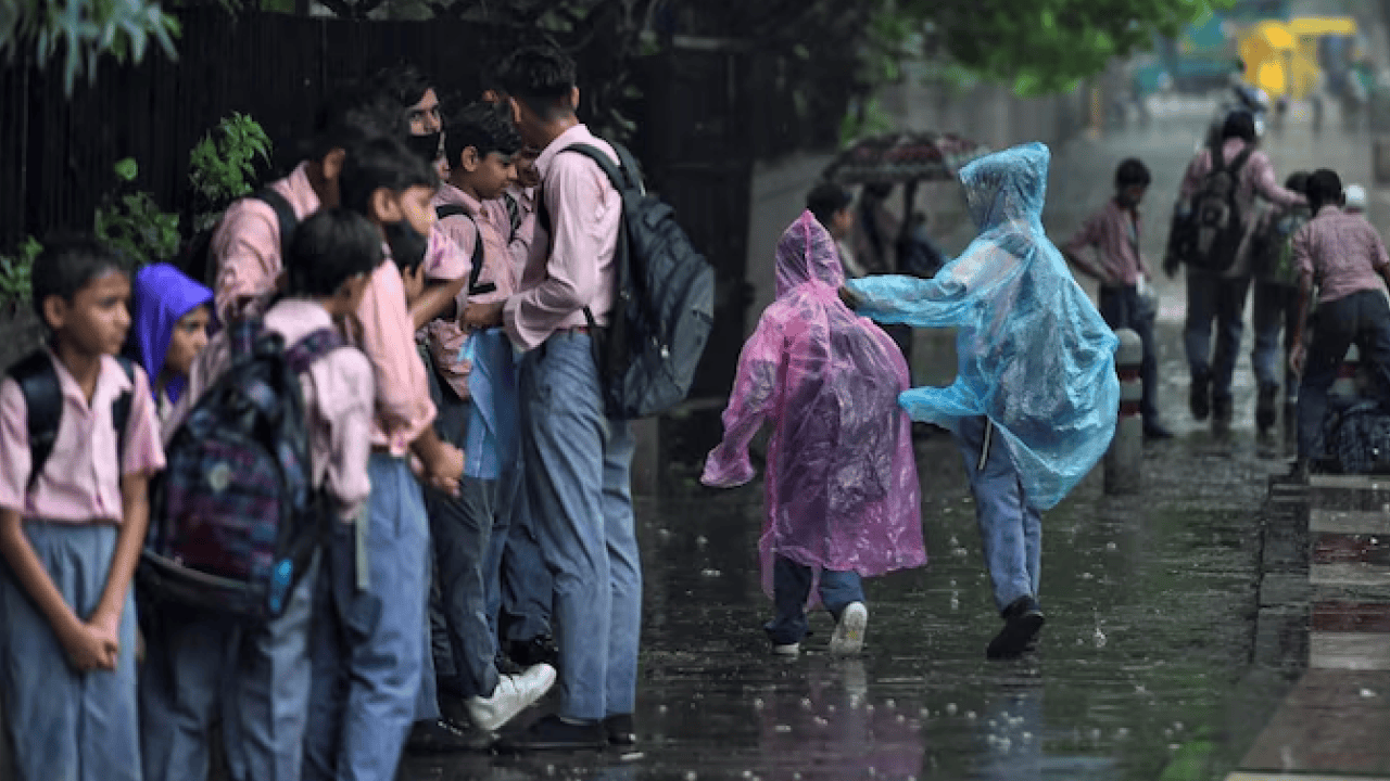 Students walking through a waterlogged street during heavy monsoon rain as multiple Indian states announce school holidays.